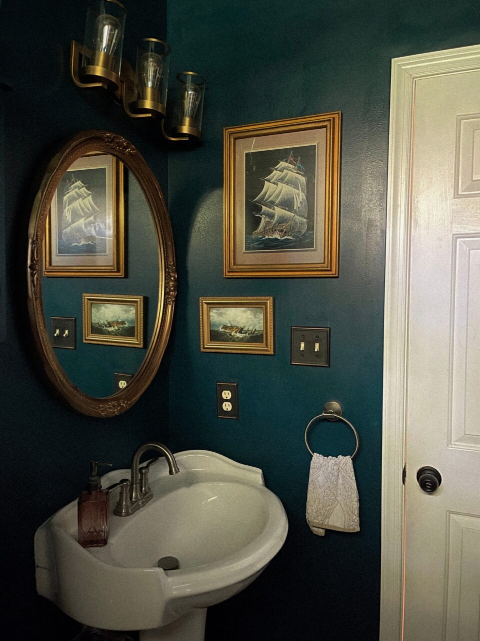 moody bathroom with gold picture frames