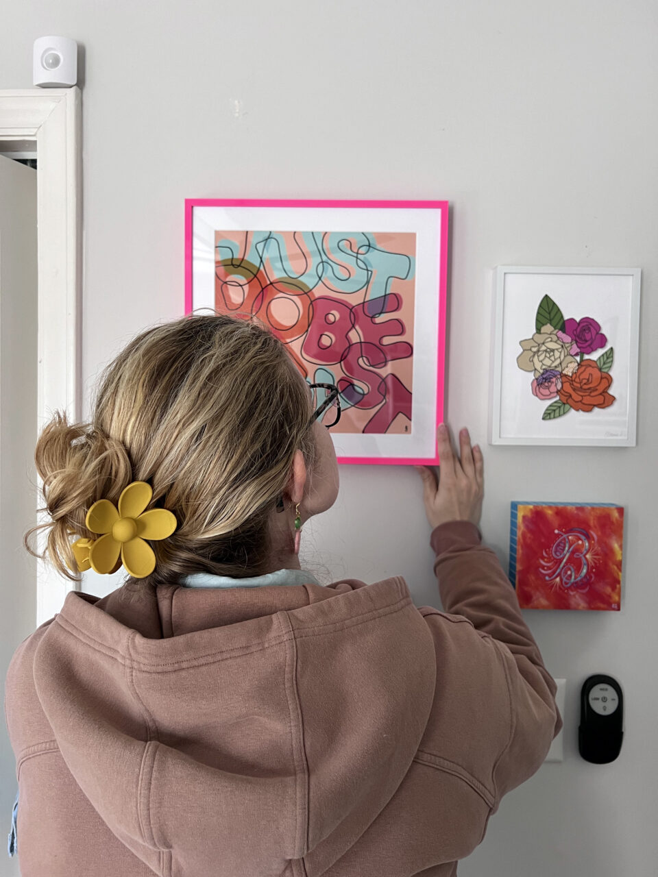 artist hanging her print in bright pink picture frame
